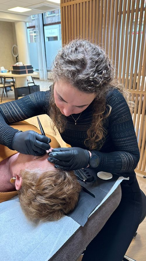 PMU-specialist brengt permanente make-up aan bij de wenkbrauwen van een klant