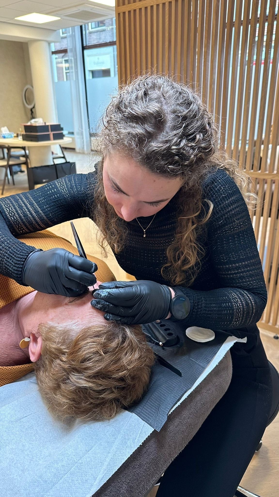 PMU-specialist brengt permanente make-up aan bij de wenkbrauwen van een klant