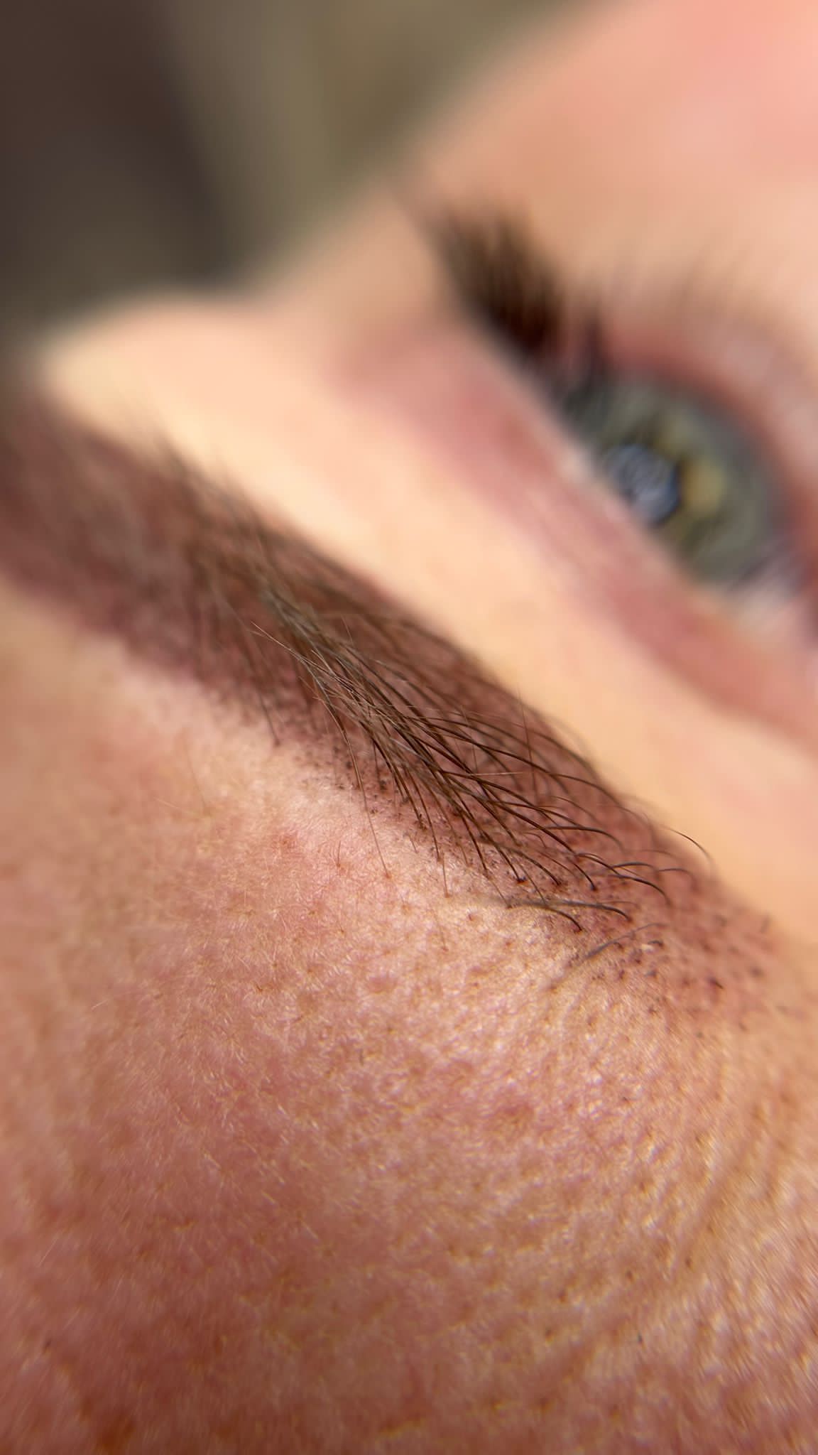 Close-up van een genezen wenkbrauw met fijne haartjes na permanente make-up