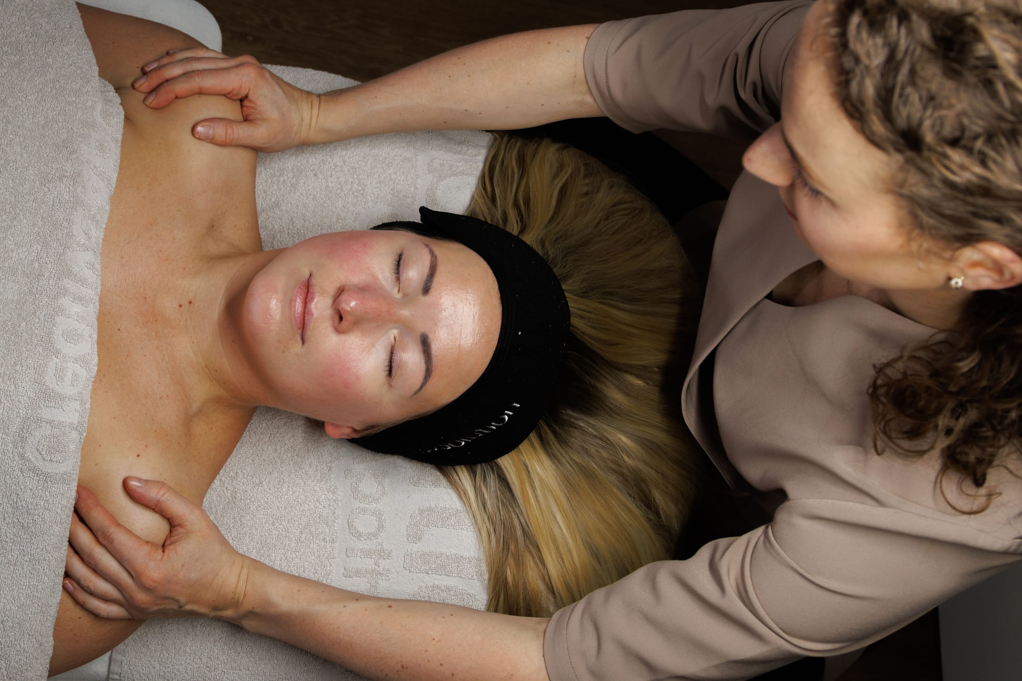 Nek- en schoudermassage tijdens een gezichtsbehandeling, van bovenaf gezien