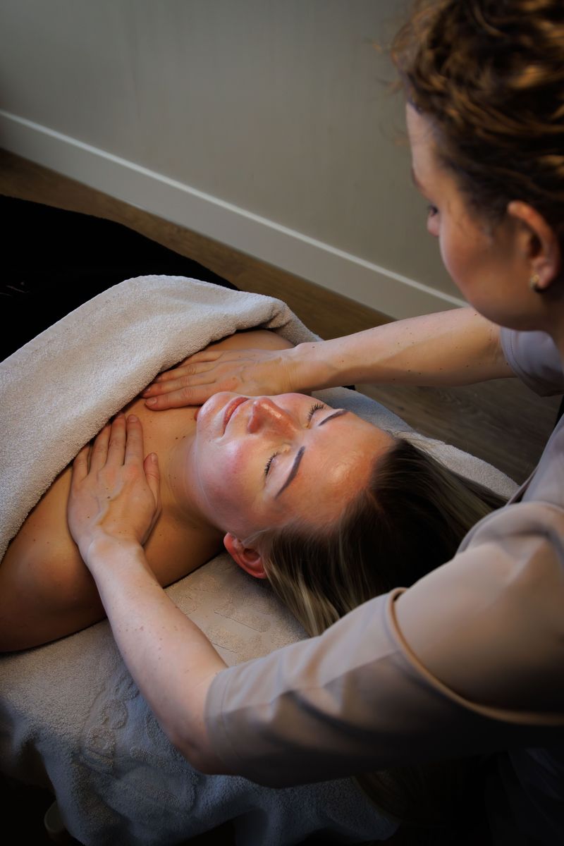 Ontspannende nek- en schoudermassage bij een klant die met gesloten ogen op de behandelstoel ligt
